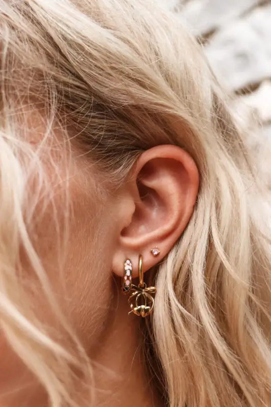 Oor met verschillende gouden oorringen van Label Kiki Kiki Pink Flower met kleurrijke details zorgen